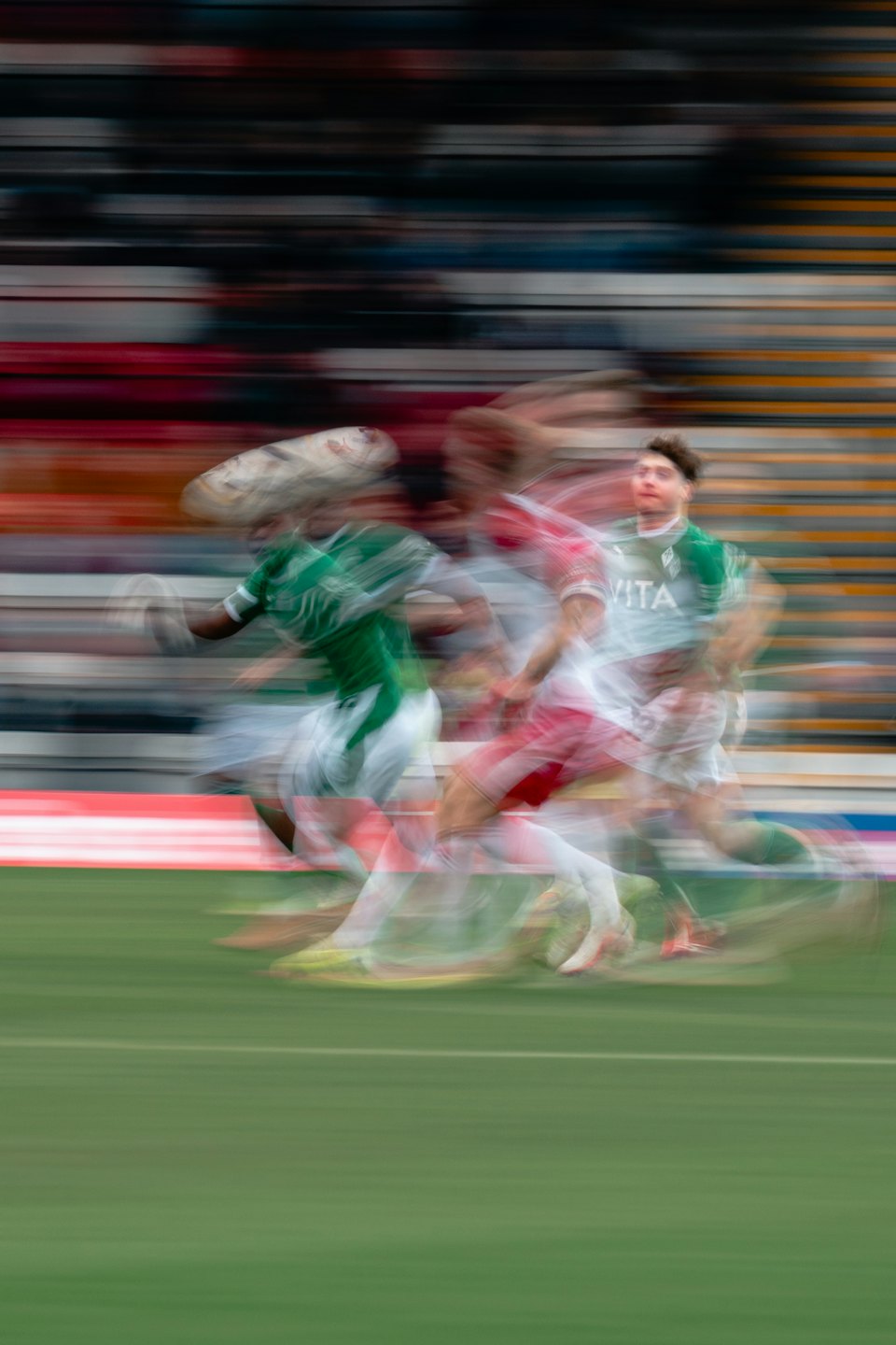 Atleti in maglie colorate corrono su un campo sportivo verde.