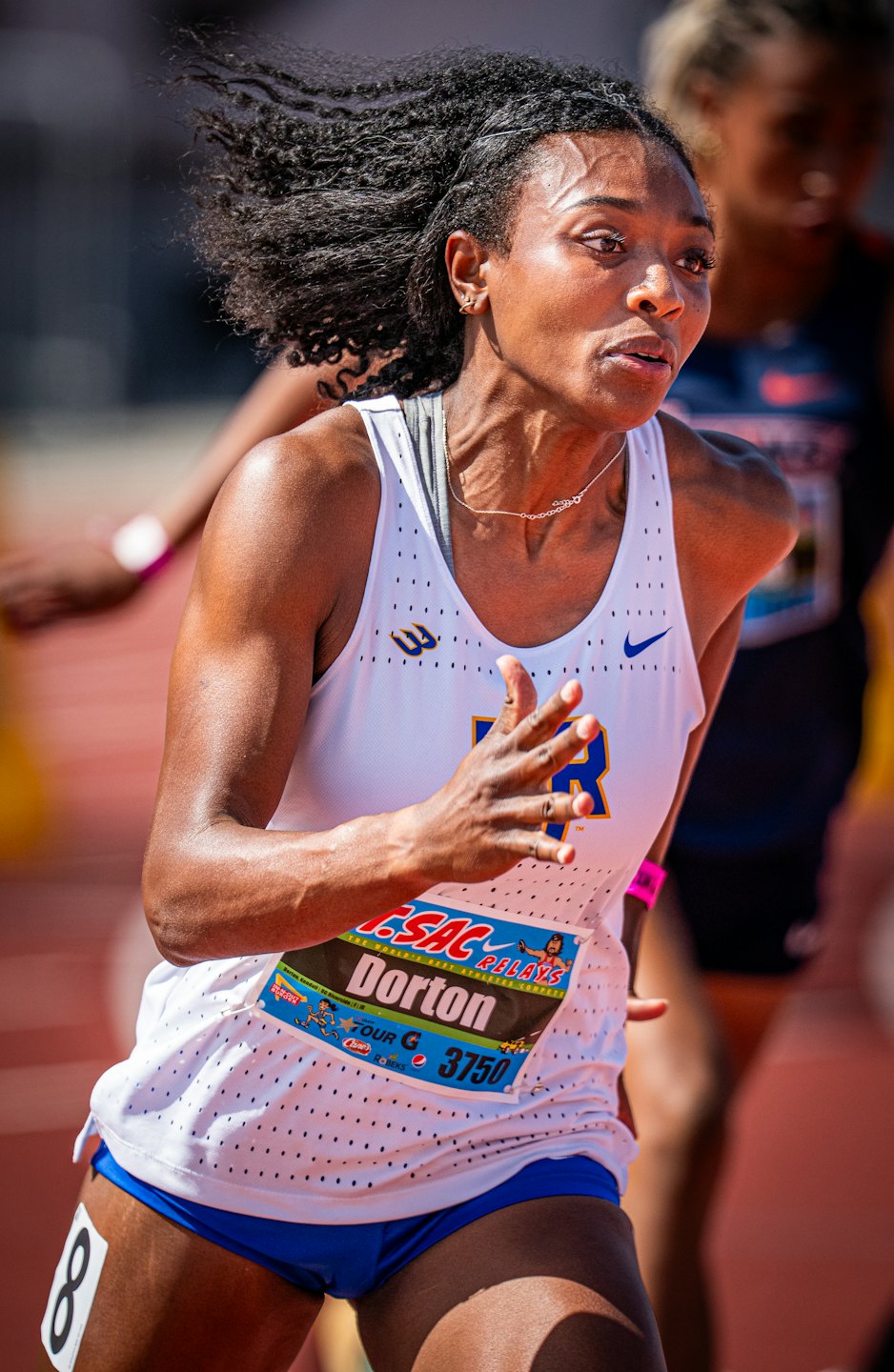 Atleta che corre in una competizione su pista indossando una divisa.