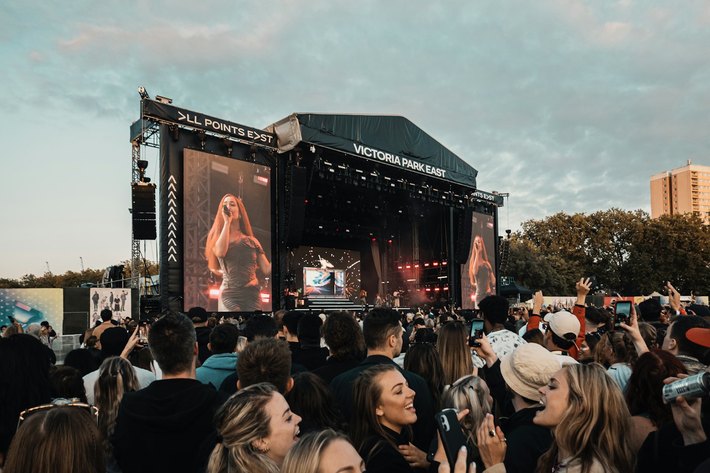 Folla di giovani a un festival musicale all'aperto che filma un artista sul palco.