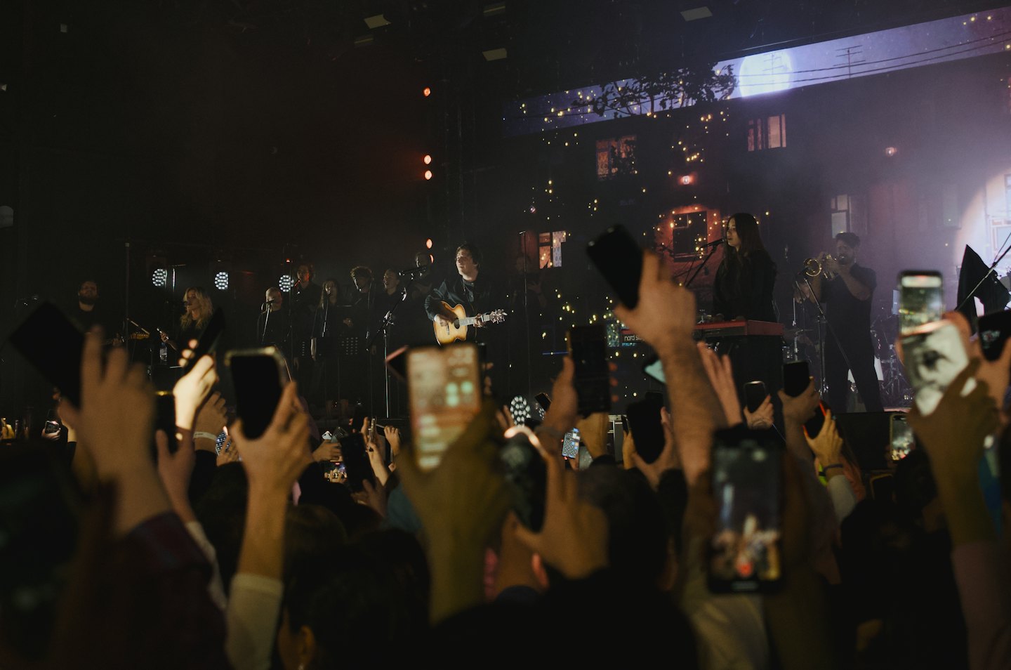 I partecipanti a un concerto filmano una band sul palco con gli smartphone.
